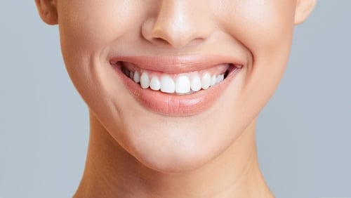 A close-up of a smiling woman, showcasing healthy and bright white teeth.