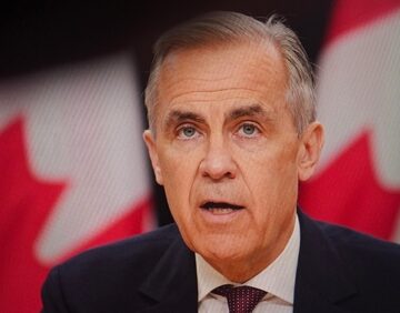 Canadian Prime Minister Mark Carney delivers a speech with Canadian flags in the background