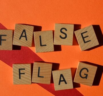 Wooden tiles spelling out the phrase "False Flag" against an orange background.