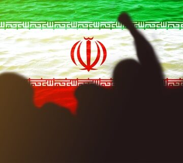 Silhouettes of people raising fists symbolizing protest, solidarity, or revolution with the Iranian flag in the background.