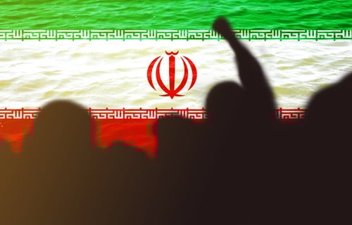 Silhouettes of people raising fists symbolizing protest, solidarity, or revolution with the Iranian flag in the background.