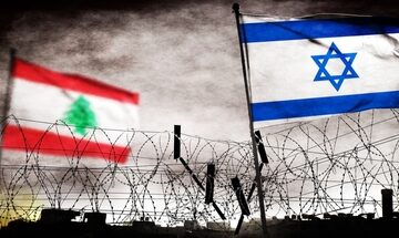 The flags of Lebanon (left) and Israel (right) positioned behind a barbed-wire fence.
