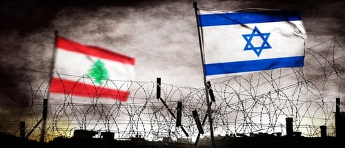 The flags of Lebanon (left) and Israel (right) positioned behind a barbed-wire fence.