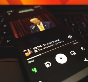 A smartphone displaying an episode of the podcast "The Joe Rogan Experience" featuring Donald Trump.