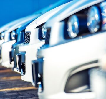 A row of white cars parked at a car dealership lot.