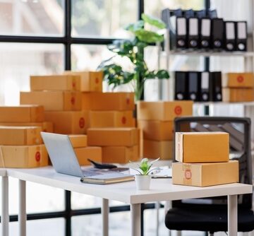 Photo of an e-commerce shipping workstation with numerous brown cardboard boxes used for packaging products for delivery.