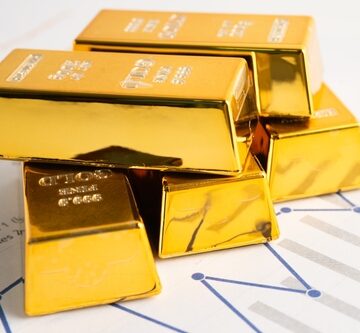 A collection of 24-karat gold bars resting on a financial graph.