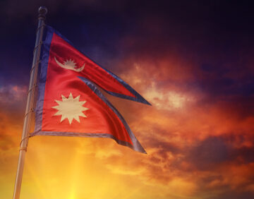 The national flag of Nepal, unique for being the only non-rectangular national flag in the world, waving in the wind before a brilliant sunrise