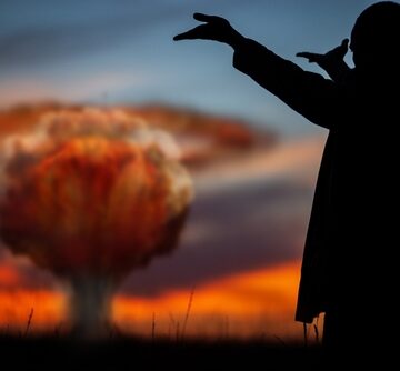 Silhouette of a man in a suit watching an atomic explosion.