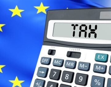 A calculator with "TAX" displayed on its screen positioned against a background of the European Union flag.