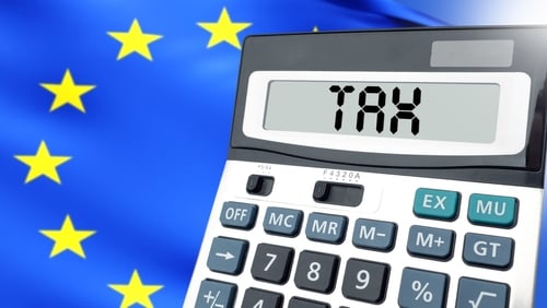 A calculator with "TAX" displayed on its screen positioned against a background of the European Union flag.