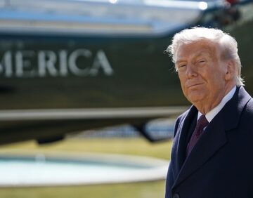 Donald Trump departing the White House with Marine One in the background.