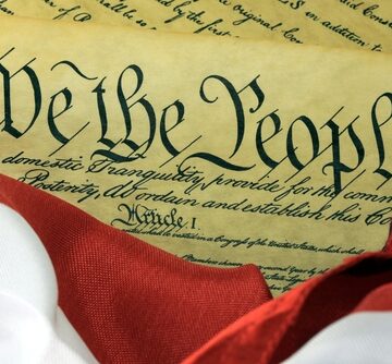 The preamble of the United States Constitution superimposed on an American flag with the text "We the People" prominently featured.