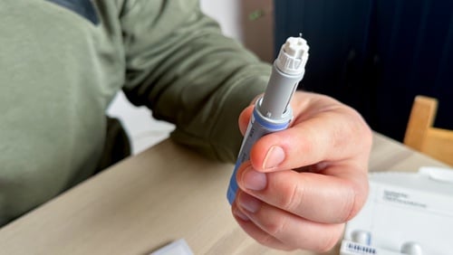 A person holding a pre-filled injection pen, such as those used for Ozempic or Wegovy to treat type 2 diabetes or for weight management.