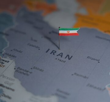 A political map of the Middle East region with a small flag of Iran pinned directly over the country.