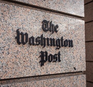 The Washington Post logo, set against a granite stone wall exterior, at the headquarters in Washington, D.C.