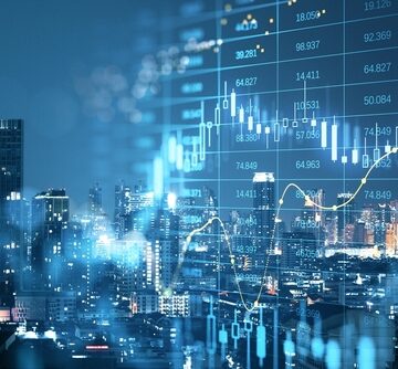 Finance and business concept, highlighting investment graphs overlaid with coin stacks on a table.