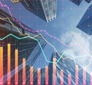 Concept image of financial trends and commercial real estate displaying a financial stock market chart overlaid on a digital background of office buildings.