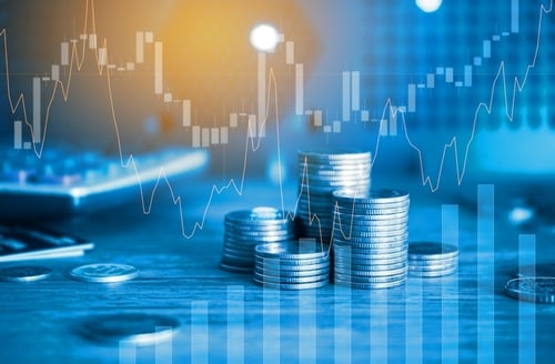 Finance and business concept, highlighting investment graphs overlaid with coin stacks on a table.