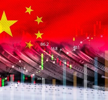 Double exposure of the flag of China, a stack of coins, and an upward stock market graph chart.