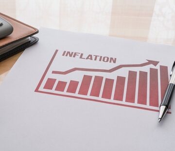 A printout of an upward inflation graph on a desk next to a pen and calculator.