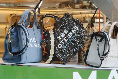 Tokyo,,Japan,-,April,30,,2021:,Bags,In,The,Window A lineup of Marc Jacobs "The Tote Bag" handbags in various materials and patterns.