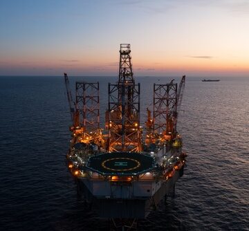 Aerial view of an offshore jack-up drilling rig at sunset, often used for exploration and development in the oil and gas industry.