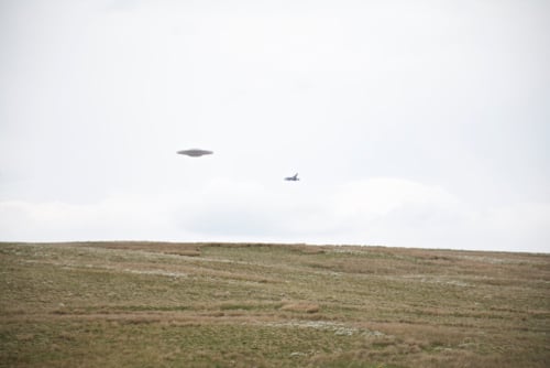 This image is a widely circulated CGI recreation of a photo titled "Flying saucer UFO over grassy moor escorted by Tornado Jet Fighter."