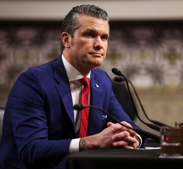Photo of Pete Hegseth, who was confirmed as the United States Secretary of Defense in January 2025, sitting in front of a microphone.