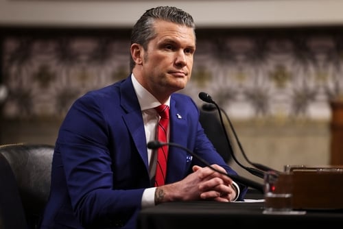 Photo of Pete Hegseth, who was confirmed as the United States Secretary of Defense in January 2025, sitting in front of a microphone.