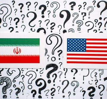 Iran,And,Usa,Flags,Rest,On,Background,Filled,With,Hand The national flags of Iran (left) and the United States (right) set against a background of question marks.