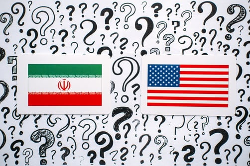 Iran,And,Usa,Flags,Rest,On,Background,Filled,With,Hand The national flags of Iran (left) and the United States (right) set against a background of question marks.