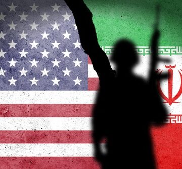 Flag,Of,Usa,And,Iran,Painted,On,A,Concrete,Wall A silhouette of a soldier against the flags of the United States and Iran separated by a large crack.