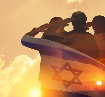 Double,Exposure,Of,Silhouettes,Of,A,Soliders,And,The,Sunset Silhouettes of soldiers saluting against a desert sunset, with the Israeli flag superimposed over the soldiers.