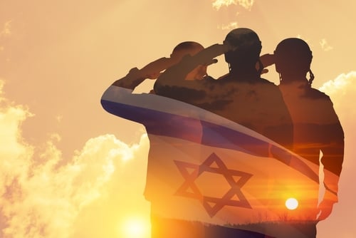 Silhouettes of soldiers saluting against a desert sunset, with the Israeli flag superimposed over the soldiers.