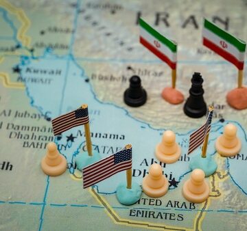 Conceptual,Representation,Of,The,Geopolitical,Conflict,Between,Iran,And,The Conceptual representation of geopolitical map representing the strategic tensions and military presence in the Persian Gulf region, with miniature flags marking specific state actors, Iranian flags placed on Iran, U.S. flags across the waters and neighboring Gulf Arab states, and chess pieces distributed across the map.