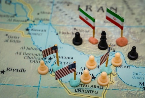Conceptual,Representation,Of,The,Geopolitical,Conflict,Between,Iran,And,The Conceptual representation of geopolitical map representing the strategic tensions and military presence in the Persian Gulf region, with miniature flags marking specific state actors, Iranian flags placed on Iran, U.S. flags across the waters and neighboring Gulf Arab states, and chess pieces distributed across the map.
