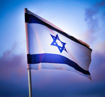 The national flag of Israel waving in the wind against a blue sky.