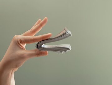 A person's hand pinching a folded stack of banknotes (paper money).