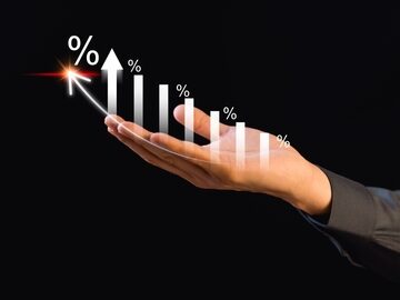 A hand holding in its palm a upward arrow and ascending percentage symbols signify rising performance, development, and success.