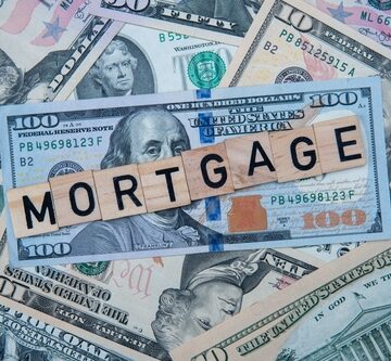 The,Word,Mortgage,Overlaid,On,A,Background,Of,U.s.,Dollar Financial concepts image with U.S. dollar bills, specifically featuring 100-dollar and 50-dollar notes spread across the background and letter tiles spelling the word "MORTGAGE" placed on top of the money.