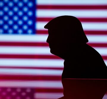 A Donald Trump silhouette in front of a blurred U.S. flag.