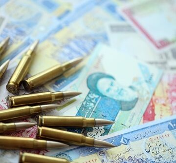 A pile of bullets atop a table covered with Iranian Rials.