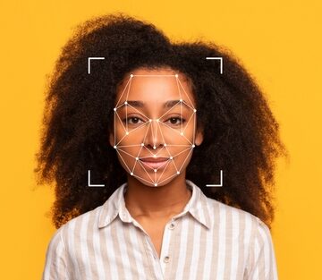 A,Young,Black,Woman,With,Curly,Hair,Stands,In,Front A young woman's face mapped as a conceptual illustration of facial recognition technology.