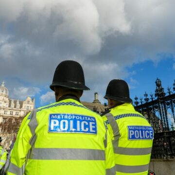 Metropolitan Police officers on duty in London near the Palace of Westminster, recognizable by Big Ben in the background.