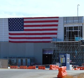A Meta data center under development with a large American flag prominently displayed on the building exterior.