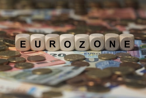 Eurozone,-,Cube,With,Letters,,Money,Sector,Terms,-,Sign White wooden cubes spelling "EUROZONE" placed on top of various Euro banknotes and coins.