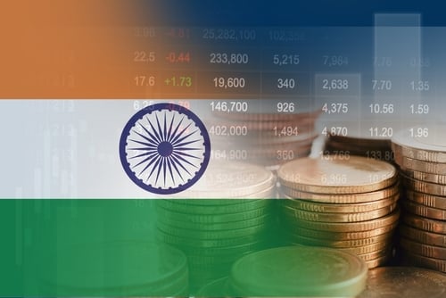 The national flag of India overlaid with a trading chart and stacks of coins.
