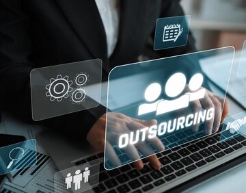 Outsourcing concept showing a person in a business suit using a laptop while digital overlays show icons related to collaboration, delegation, and global workforce management. Outsourcing concept showing a person in a business suit using a laptop while digital overlays show icons related to collaboration, delegation, and global workforce management.
