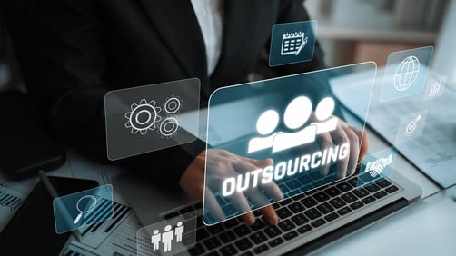 Outsourcing concept showing a person in a business suit using a laptop while digital overlays show icons related to collaboration, delegation, and global workforce management.